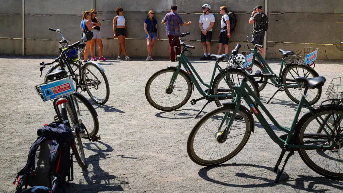 Group on rental bikes beside a remaining stretch of the Berlin Wall on a Berlin WW2 bike tour