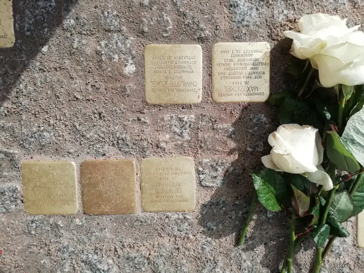 Group of Stolpersteine on a Berlin street with white roses